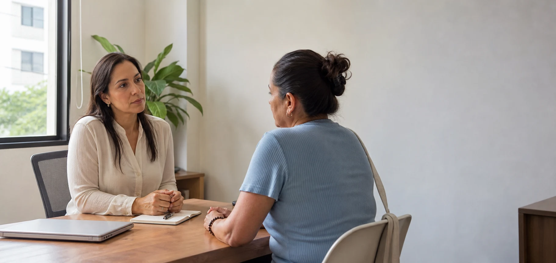 Médica conversa con una paciente en un consultorio luminoso.